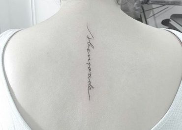 Tatuajes pequeños para mujer con caligrafía artística en la espalda